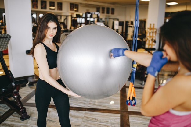 Two beautiful athletic girls are engaged in the gym