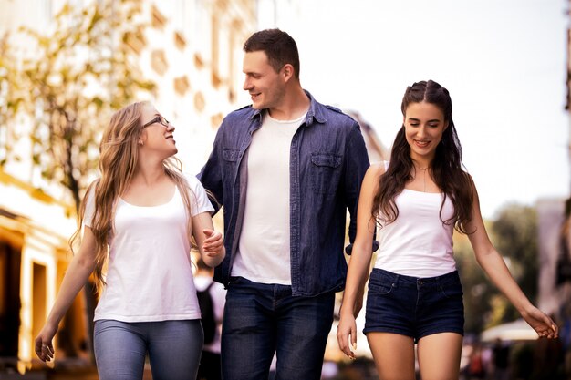 Two beautiful caucasian girls and a boy are walking through the street