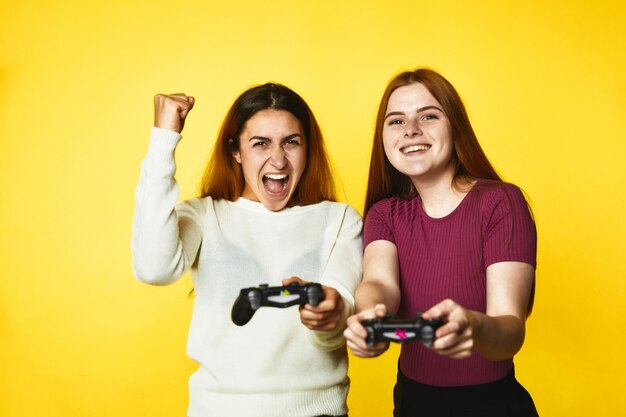 Two beautiful caucasian girls with wireless joystick