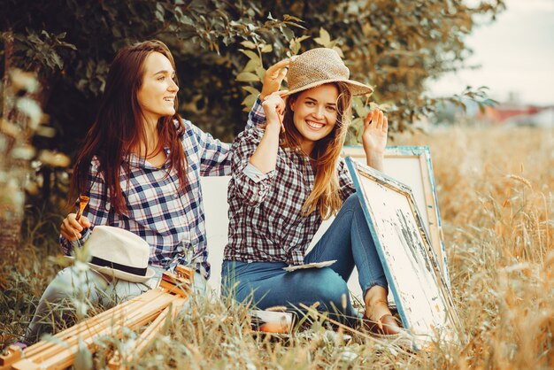 Two beautiful girls drawing in a field