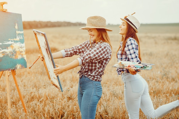 Two beautiful girls drawing in a field