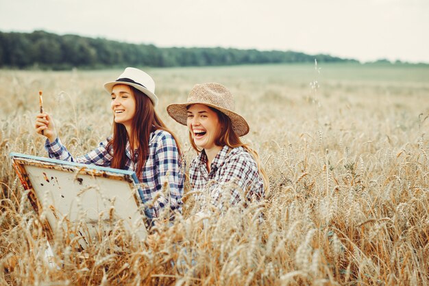 Two beautiful girls drawing in a field