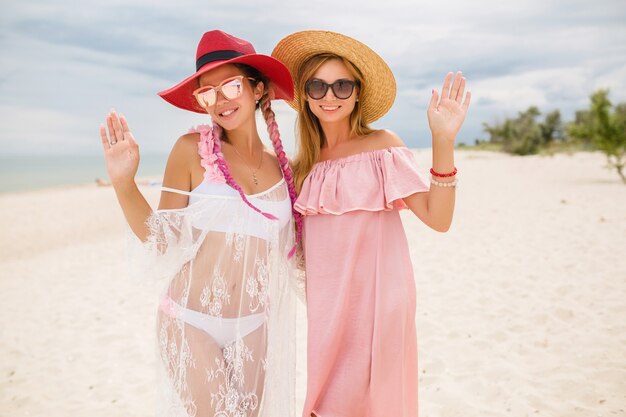 Two beautiful stylish woman at beach on vacation, summer style,