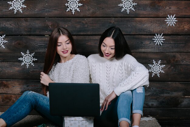 Two beautiful women siting on the floor with a laptop