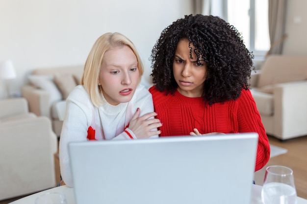 Due belle donne che usano il laptop per una videochiamata online e brindano online con i loro amici festa online per gli amici