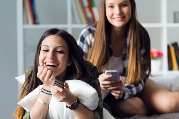 two beautiful young woman staying on sofa at home.