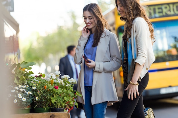 Two beautiful young women walking and talking in the street.