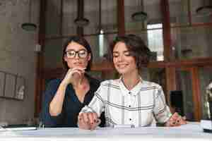 Free photo two beauty pretty smiling women sitting by the table