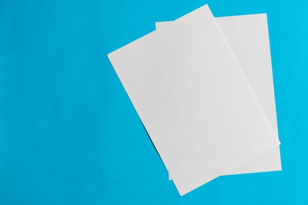 Two blank papers on blue backdrop