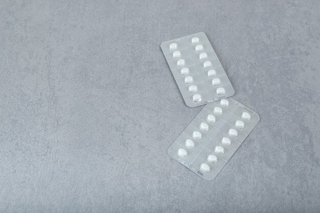 Two blisters with pills on a gray surface