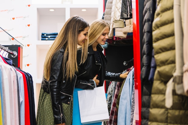 Two blonde young women looking at clothes in the shopping store