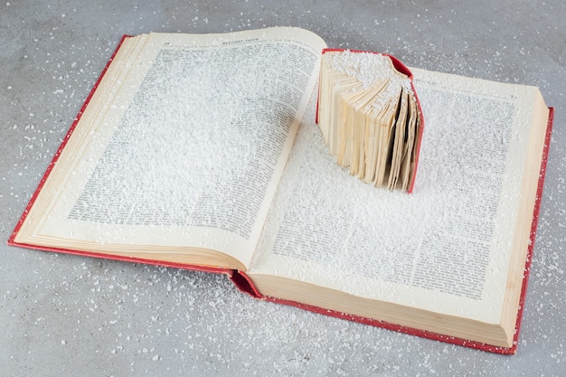 Foto gratuita due libri visualizzati su una superficie di marmo ricoperta di polvere di cocco