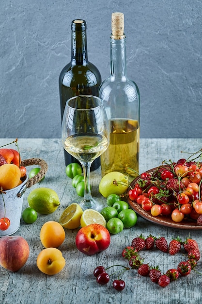 夏の新鮮な果物の束と大理石のテーブルに2本のボトルとグラスワイン