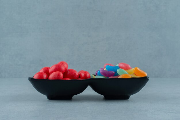 Две чаши, полные разноцветных конфет бобов на белой поверхности