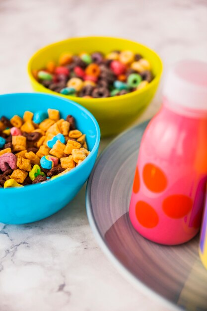Two bowls of cereals with bottle of milk 