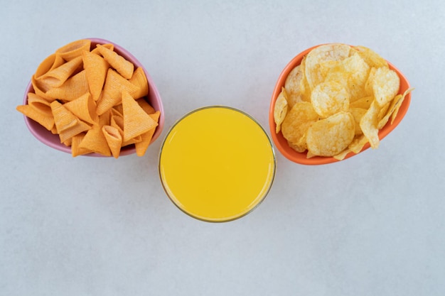 Two bowls of chips and glass of juice