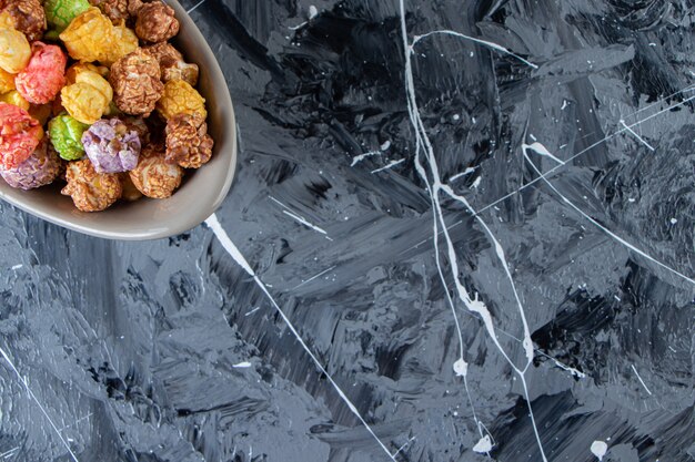 Two bowls of colorful tasty popcorns on marble surface.