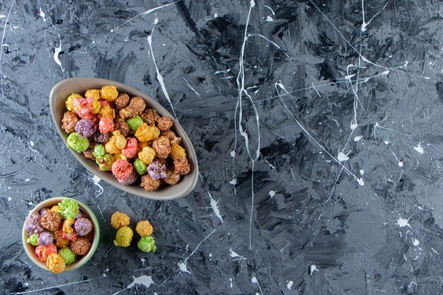 Two bowls of colorful tasty popcorns on marble surface. 