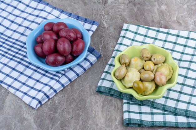 Two bowls of pickled vegetables and plums with tablecloths.