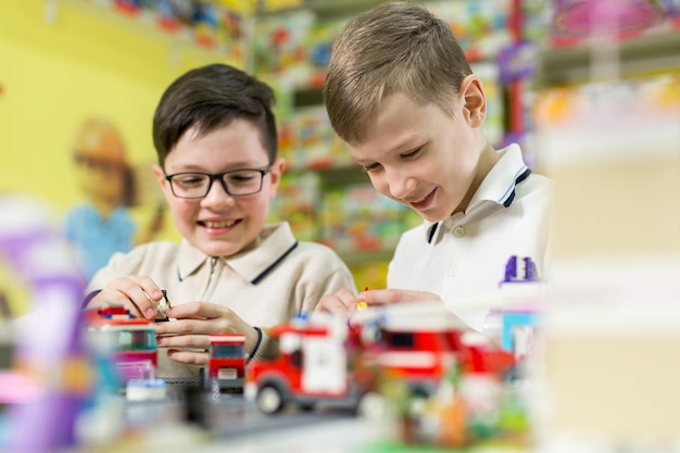 Два мальчика играют вместе с цветными пластиковыми кубиками в школе игрового центра