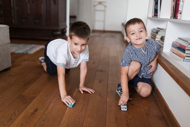 Бесплатное фото Два мальчика, играющие с игрушками на деревянном полу