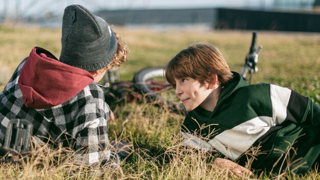 Two boys resting on grass while riding their bicycles