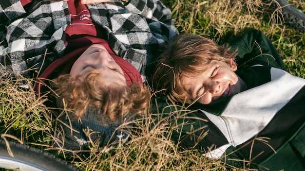 Free photo two boys resting on grass while riding their bikes