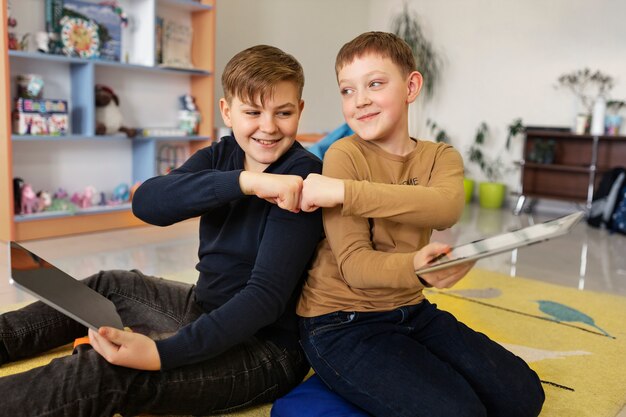 Two boys using a tablet and doing a fist bump