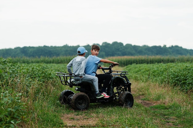 Two brothers driving fourwheller ATV quad bike Happy children moments