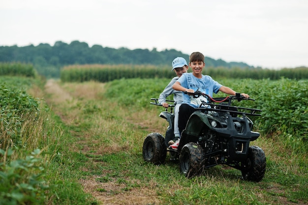 Two brothers driving fourwheller ATV quad bike Happy children moments