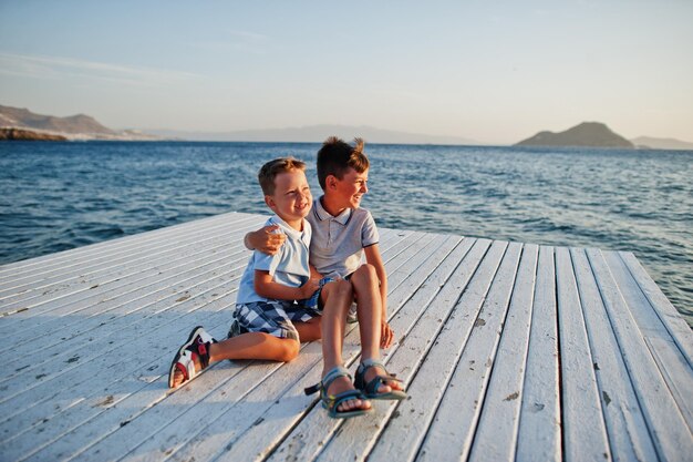 Two brothers sitting at Turkey resort on pier against Mediterranean sea