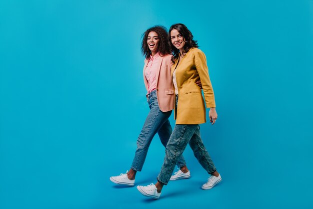 Two brunette woman walking across studio