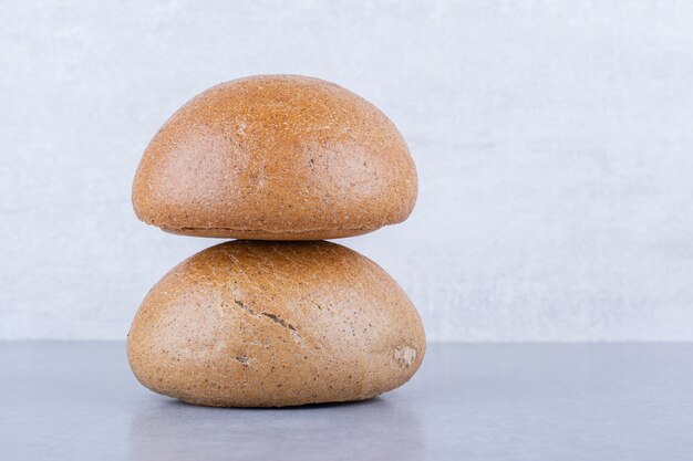 Two burger buns stacked on marble surface