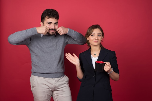 Two business partners happily standing on red wall