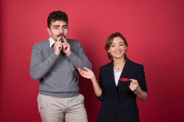 Two business partners happily standing on red wall