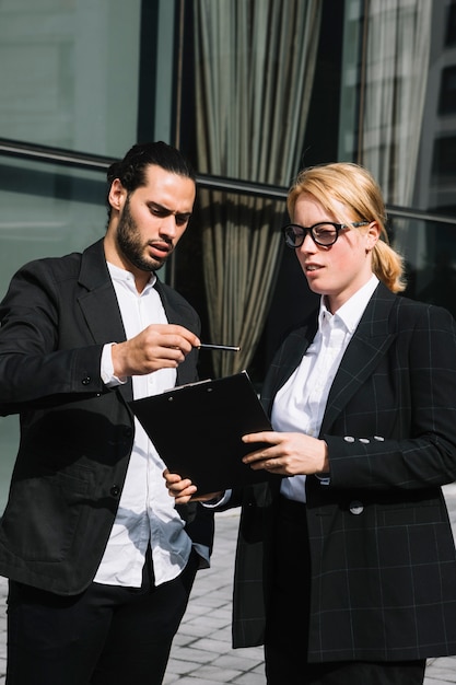 Two business people standing outside the office discussing about work