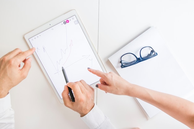 Free photo two business player pointing at graphic digital tablet with drawn graph on screen