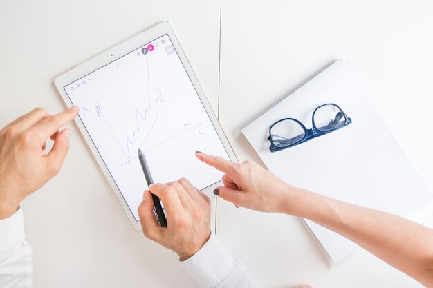 Two business player pointing at graphic digital tablet with drawn graph on screen