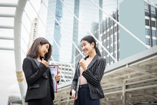 Two business woman standing and discussing in front of the office. Business working concept.