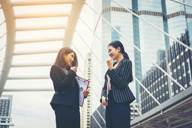 Two business woman standing and discussing in front of the office. Business working concept.