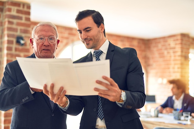 Free photo two business workers working together speaking and reading documents standing at the office