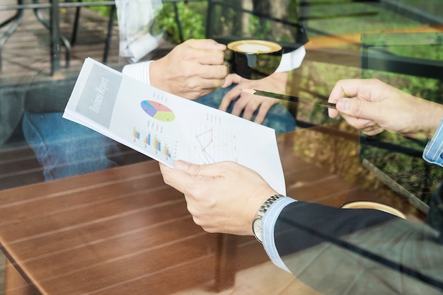 Free photo two businessman discussing their chart in coffee shop