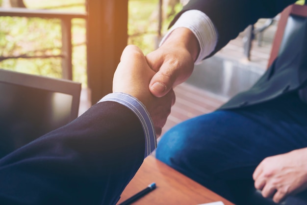 Two businessman shake hand in coffee shop