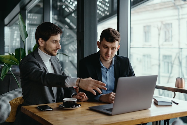 Two businessmen pointing laptop screen while discussing