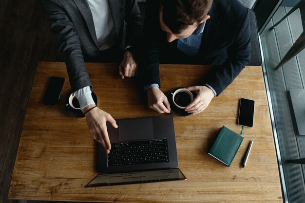 Two businessmen pointing laptop screen while discussing