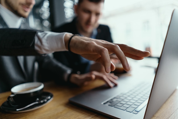 Two businessmen pointing laptop screen while discussing