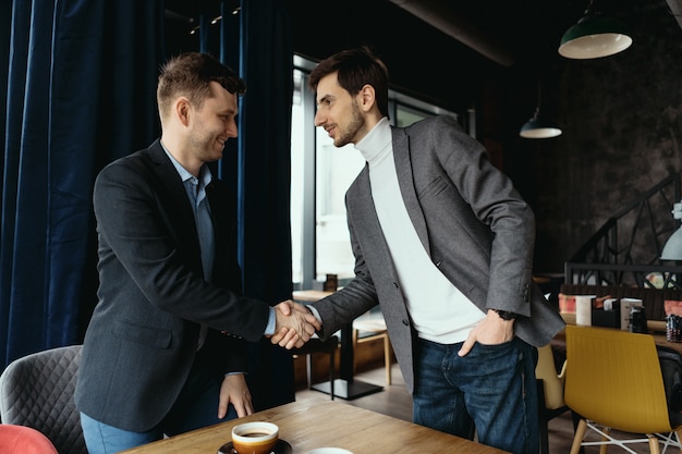 Two businessmen shaking hands while meeting in lobby