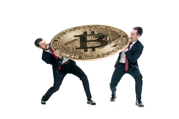 Two businessmen in suits holding business icon - big bitcoin isolated on white background. crypto-currency coins, litecoin, ethereum, e-commerce, finance concept. collage