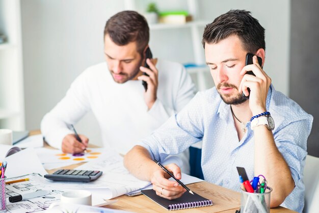 Two businessmen talking on cellphone