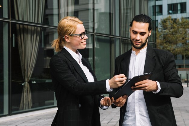 Two businesspeople discussing business project over clipboard at outdoors